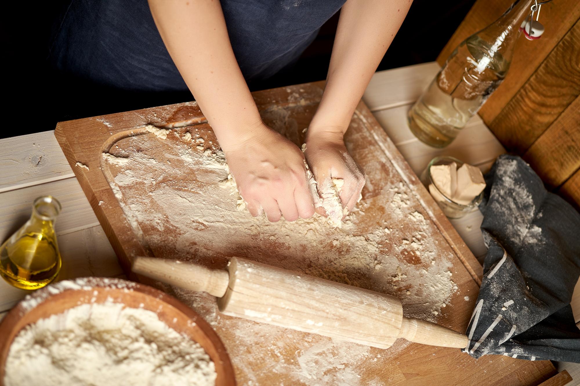 Close-up of hands kneading dough on a wooden board