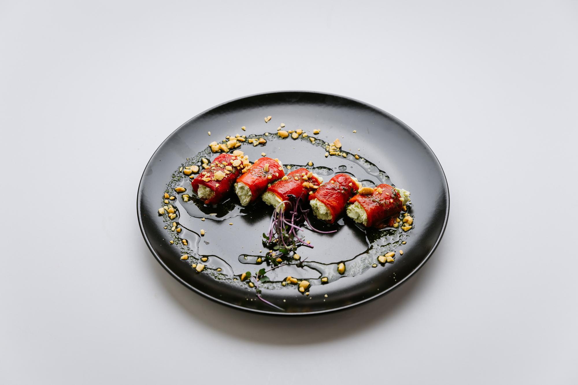 Artful plated main course on dark plate with garnish