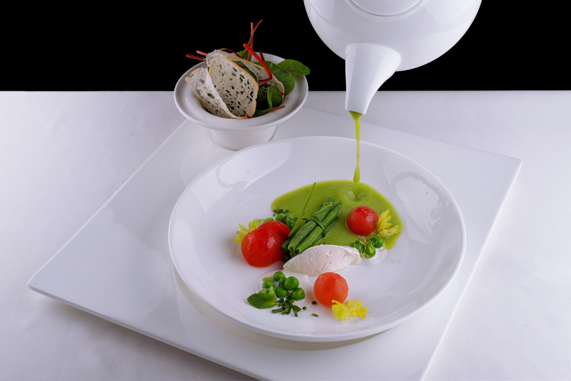Chef arranging a plated dish with herbs and sauce